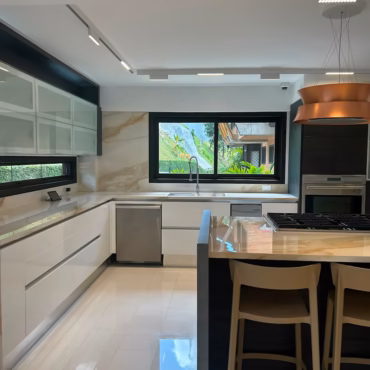 Diseño interior de cocina residencial moderna con isla central, carpintería a medida y acabados de lujo