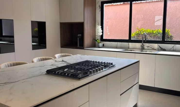 Vista general de cocina moderna con isla central, carpintería a medida y acabados de lujo