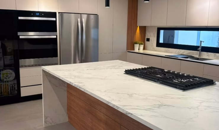 Diseño de interiores de cocina moderna con isla central, electrodomésticos de alta gama y carpintería a medida