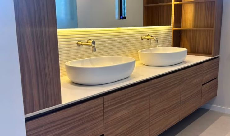 Detalle de doble lavabo sobreencimera, grifería dorada y espejo con iluminación LED
