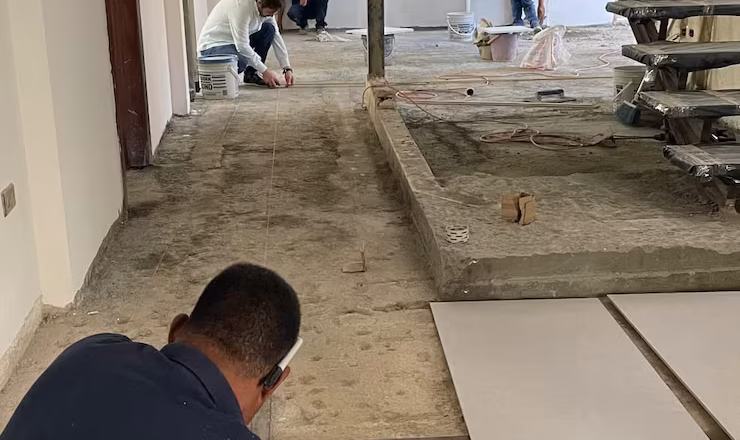 Personal de la constructora realizando medición para colocación adecuada de pisos en interiores